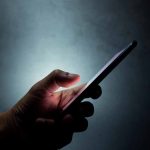 Hand holding a smartphone in the dark