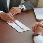 Handing in a resignation letter across a table
