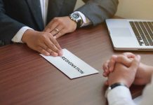 Handing in a resignation letter across a table