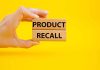 Hand holding Product Recall blocks on yellow background