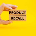 Hand holding Product Recall blocks on yellow background