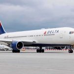 Delta Airlines airplane on airport runway cloudy sky