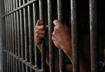 Hands gripping prison cell bars tightly