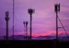 Cell towers against a purple sunset sky