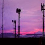 Cell towers against a purple sunset sky