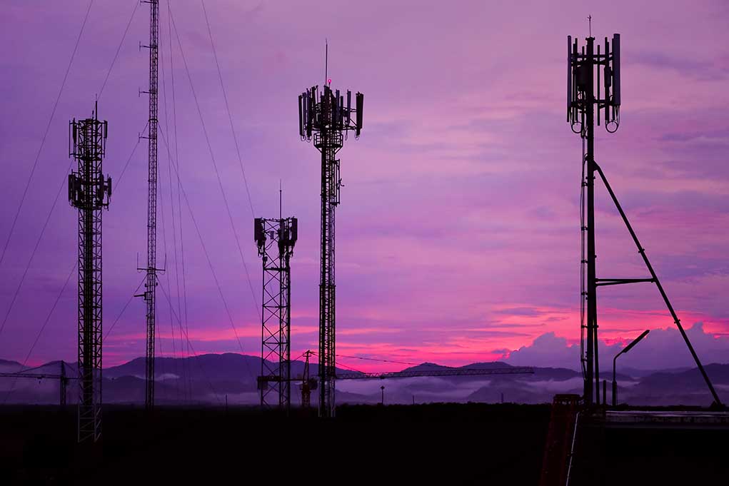 Cell towers against a purple sunset sky