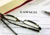 Lawsuit paperwork with glasses pen and an open book