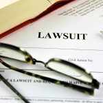 Lawsuit paperwork with glasses pen and an open book