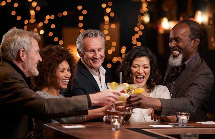 1038716299 People laughing while clinking glasses at a bar
