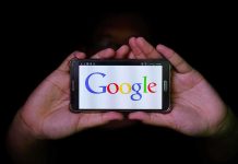 Hands holding smartphone displaying Google logo