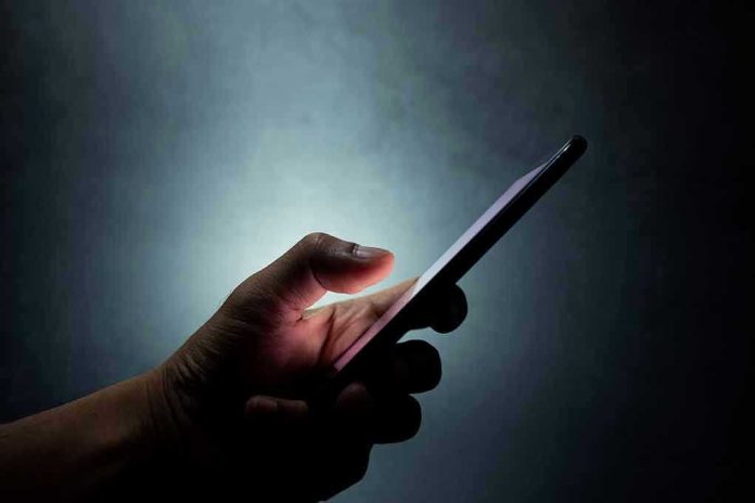 1431658976 Hand holding a smartphone in the dark