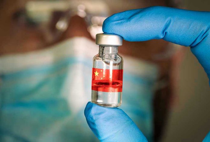 1873202461 Gloved hand holding vial with red liquid and flag