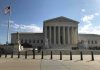 Supreme Court building with flag and people outside