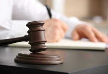 Judge's gavel on desk with person writing