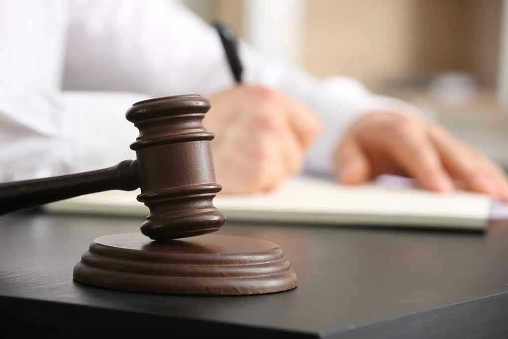 2454469737 Judge's gavel on desk with person writing