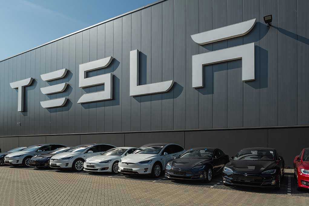 489388897 Tesla facility with parked cars in front