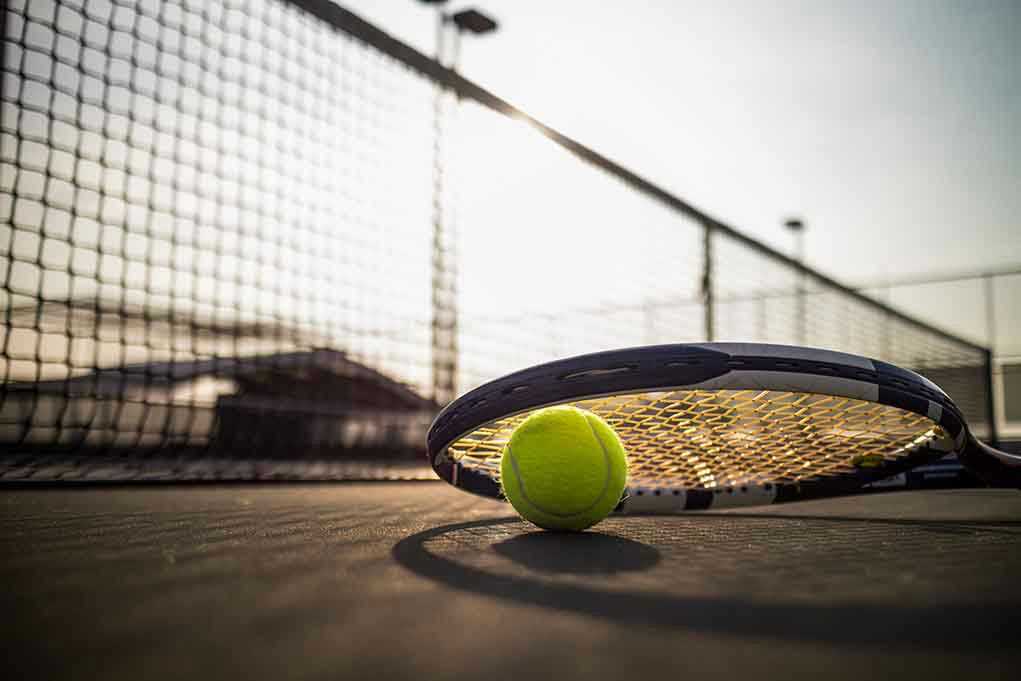 Tennis racket and ball on court near net