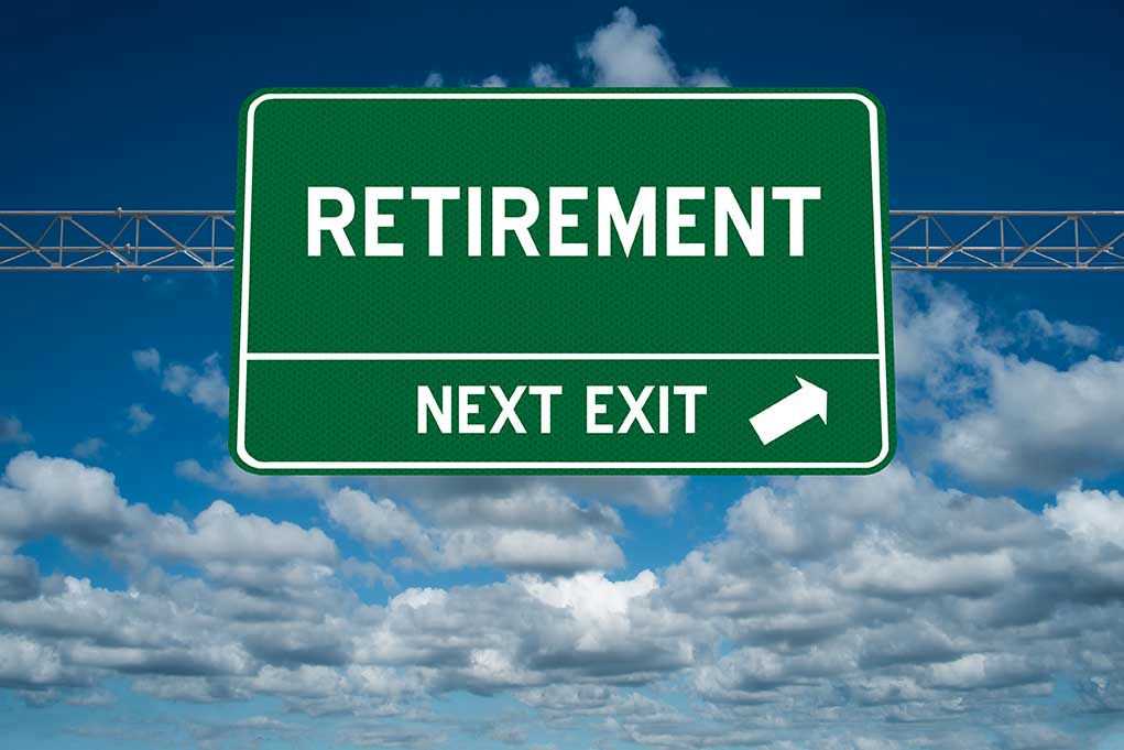 Green road sign reading retirement next exit sky background