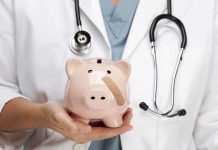 A doctor in a white coat holding a piggy bank with a bandage on it