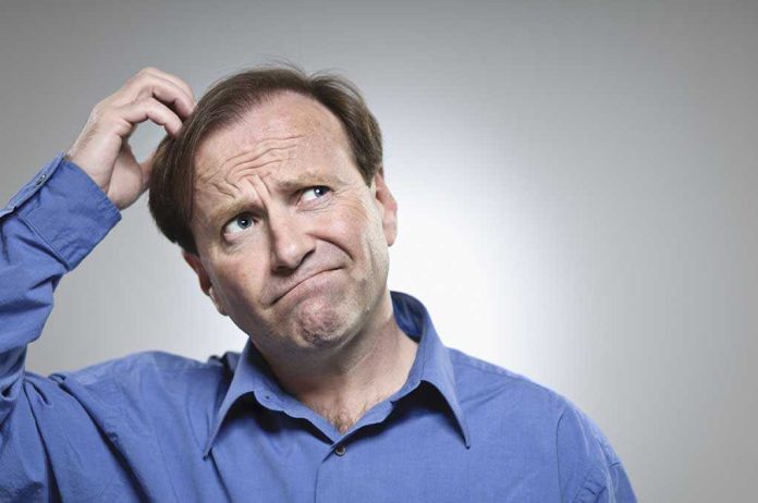 shutterstock_133739957.jpg A man in a blue shirt with a confused expression, scratching his head