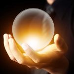 A hand holding a glowing crystal ball against a dark background