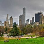 People relaxing in a park, city skyline background.
