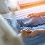 Hospital patient holding visitor's hand reassuringly