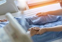 Hospital patient holding visitor's hand reassuringly