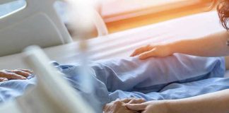 Hospital patient holding visitor's hand reassuringly