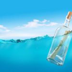 A glass bottle with a rolled-up message floating in clear blue water under a bright sky