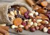 A burlap sack spilling a variety of nuts and dried fruits on a wooden table