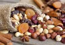 A burlap sack spilling a variety of nuts and dried fruits on a wooden table