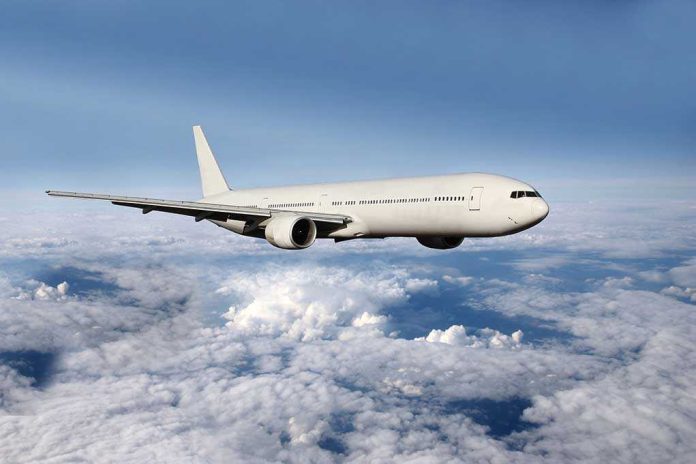 shutterstock_182272232.jpg A white airplane flying above fluffy clouds in a blue sky
