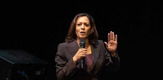 Person speaking into microphone with hand raised.