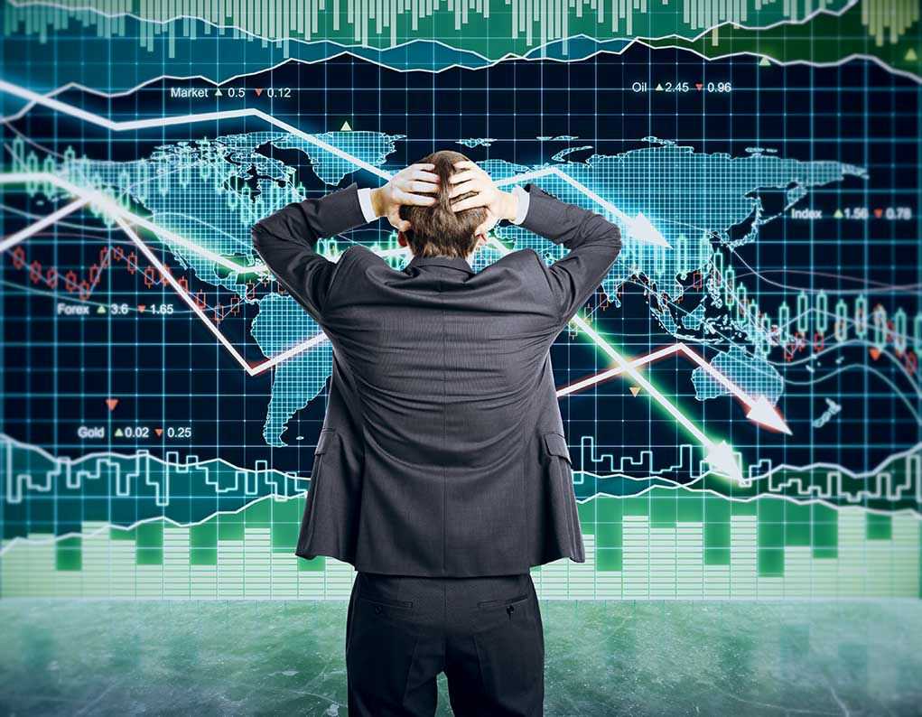 Person in front of falling stock market graph.