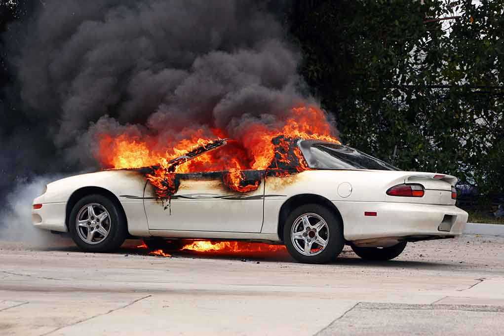 shutterstock_8681776.jpg A white car engulfed in flames with thick black smoke rising