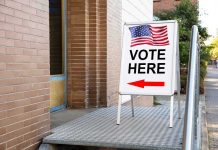 Vote Here sign with arrow and American flag.