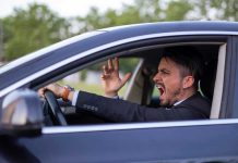 Man yelling inside a car, looking frustrated.