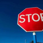Trump HALTS Government Cash For Abortions Red stop sign against a clear blue sky.