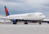 Delta Fight Meltdown Stuns Airports Around US Delta Airlines airplane on airport runway, cloudy sky.