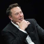 Wikipedia’s Leftist Conspiracy EXPOSED — Musk Responds Man in suit smiling, resting chin on hand.