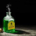 Antifreeze Murder Plots – Wives Turn Deadly Green poison bottle with cork on wooden surface.