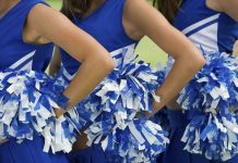 Cheerleaders in blue and white uniforms holding pom poms