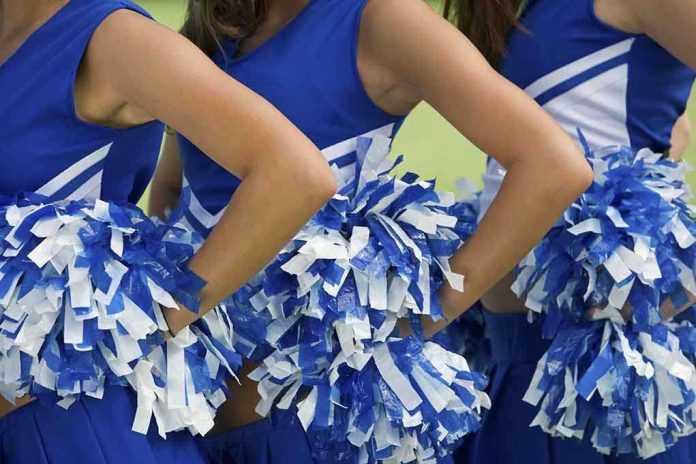shutterstock_109441577.jpg Cheerleaders in blue and white uniforms holding pom poms