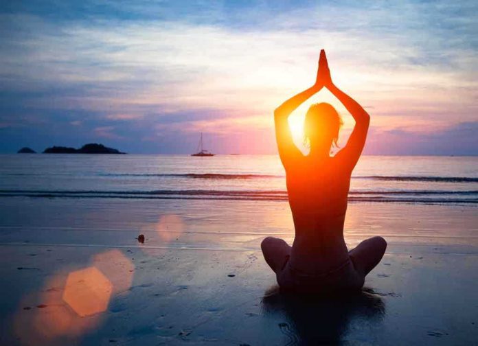 Person meditating on the beach during sunset