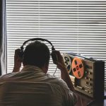 Reporter Served as SPY—CCP’s Shocking Seduction Plot Person listening to a vintage tape recorder with headphones