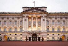 REVEALED — Shocking Royal Lease PROTECTS Prince Andrew Front view of Buckingham Palace with illuminated facade and British flag