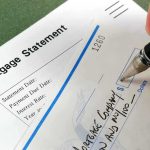 Fed’s Sudden Rate Cut — A Little Too LATE? A person writing a check on a mortgage statement