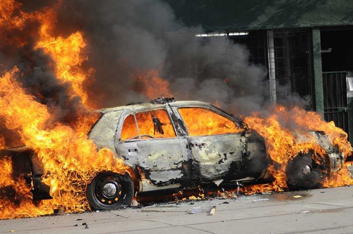 shutterstock_56871814.jpg A car engulfed in flames with thick smoke billowing into the air