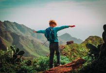 Fatal Wolf Attack Sparks Outrage in Canada Child with backpack stands on mountain, arms outstretched.